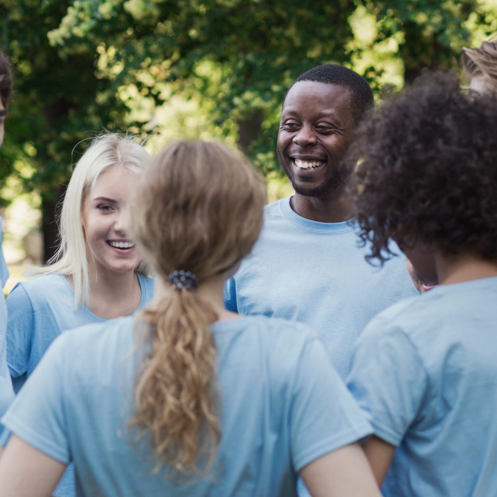 Happy volunteers standing together, support and unity training, copy space